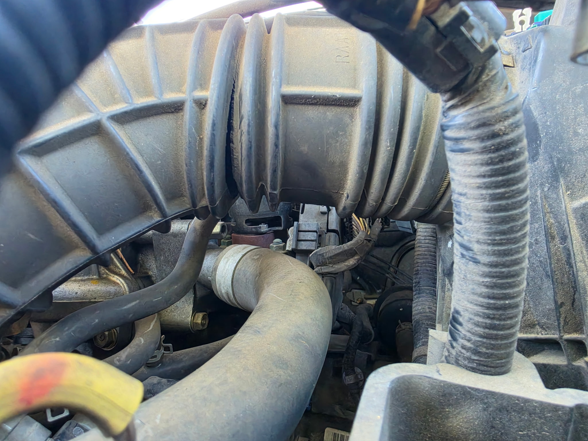 Close-up view of an engine's air intake manifold showing ribbed plastic ducting and connected intake components