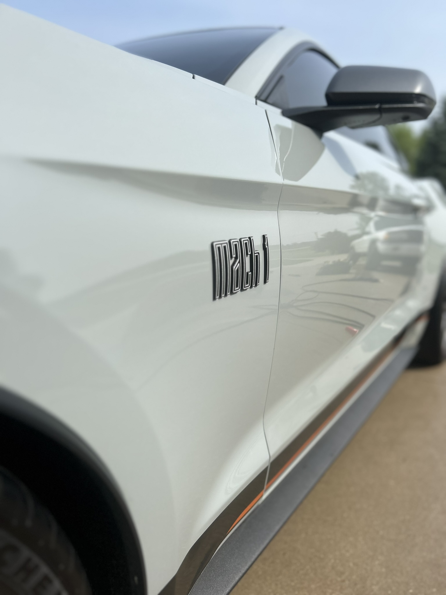 Clean white vehicle body panel and Mach badging showing reflective paint after exterior detailing
