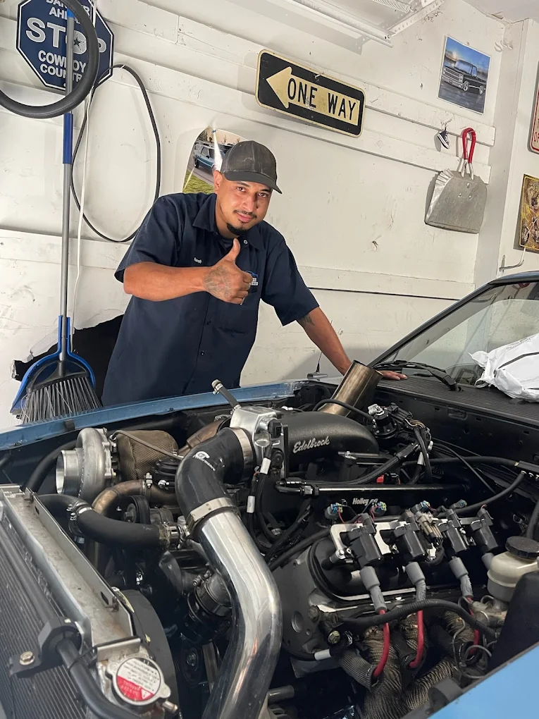 Mobile mechanic inspecting turbocharger and intake manifold on a performance engine during an on-site engine repair diagnostic