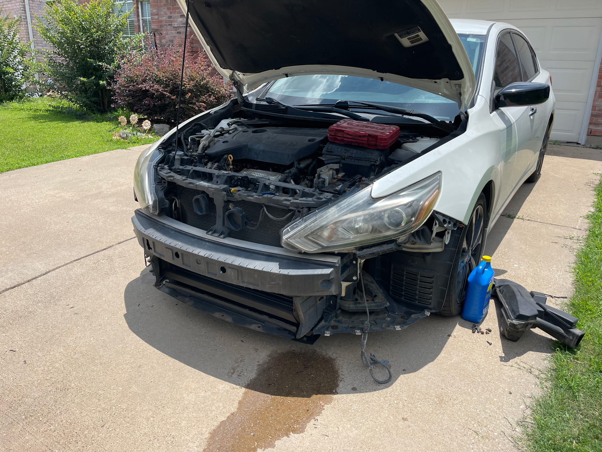 Mobile mechanic inspecting engine compartment with tools and diagnostic equipment on driveway during on-site service call